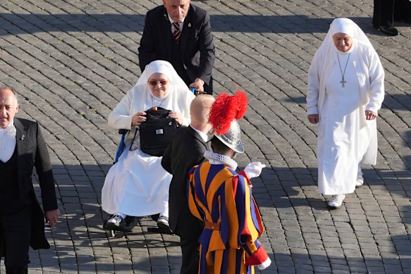 A Pontifical Swiss guard stands as two nuns arrive in St Peter’s Square.