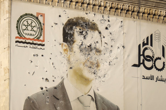 An image of Syrian President Bashar al-Assad, riddled with bullets, is seen on the facade of the provincial government office in the aftermath of the opposition’s takeover of Hama.