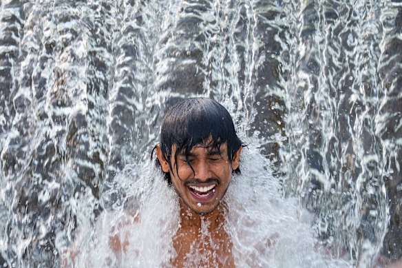 A worker cools off in a cascading river on a torrid day, outside Bragadiru, Romania.