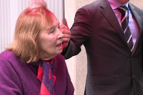 Joy Membrey at the Coroners Court. Damon Abbey is holding the umbrella.