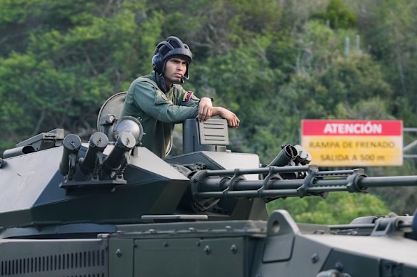 A Venezuelan soldier stands atop an armoured vehicle driving towards Caracas on Sunday.