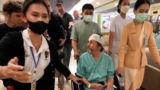 Keith Davis (centre) is whisked away and prevented from talking to reporters at Samitivej Srinakarin Hospital in Bangkok, Thailand, on Thursday.