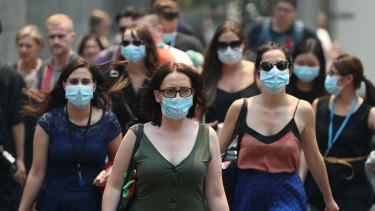 People wear face masks to protect from smoke haze as they cross a busy street in Sydney's CBD.