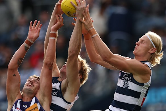 Luke Jackson of the Dockers, Mitchell Edwards and Oliver Dempsey of the Cats compete for the mark.