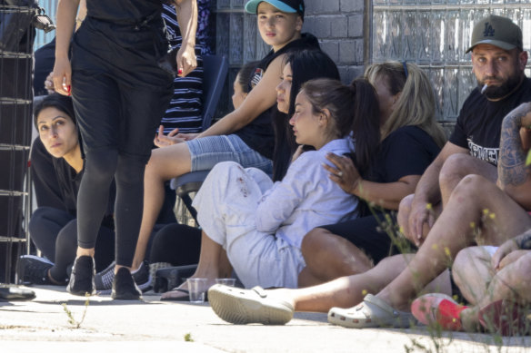 A woman with blood stained clothes is comforted at the scene.