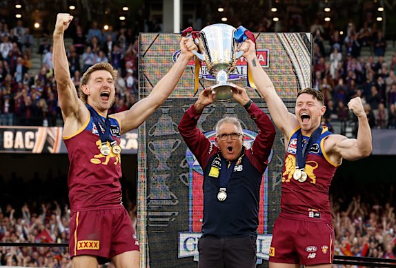 Lachie Neale lifts the 2025 premiership cup with Lions co-captain Harris Andrews (left) and coach Chris Fagan.