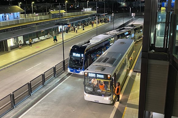 A Brisbane Metro bus manoeuvring around a rail bus parked at a busway station.