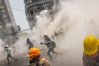 Des manifestants anti-coup d'État courent après que la police anti-émeute a tiré des gaz lacrymogènes à Yangon.