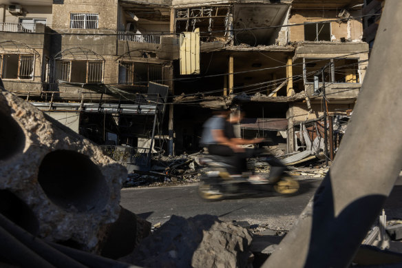 Men share a scooter ride past a building damaged by a previous Israeli strike on a residential building in Tyre, Lebanon.