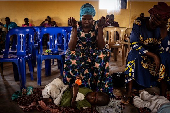 At an information session for parents with children living with disability, 44-year-old mother Winifred Achan prays for her 12-year-old son Shedrac Ogwakol.