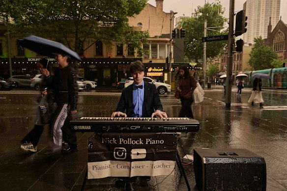 Pianist Nick Pollock busks in George Street, Sydney, on a rainy Wednesday.