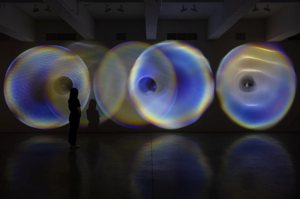 Olafur Eliasson’s 2024 work Your Psychoacoustic Light Ensemble consists of spotlight, glass lens, mirror foil, tripod, transducer, and embedded computer system.