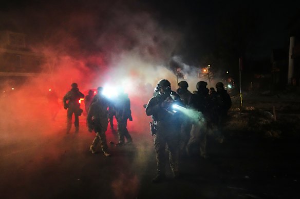 Law enforcement officers stand amid tear gas at the scene of the shooting.
