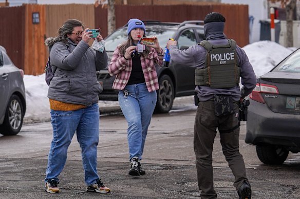 A federal agent points pepper spray at observers while conducting immigration enforcement operations.