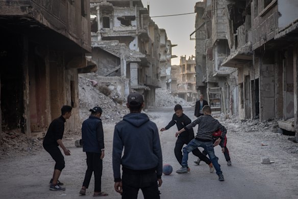 Boys play football amid destroyed buildings at the Yarmouk camp last December.