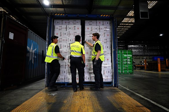 Australian Border Force officers with a container of illegal cigarettes.
