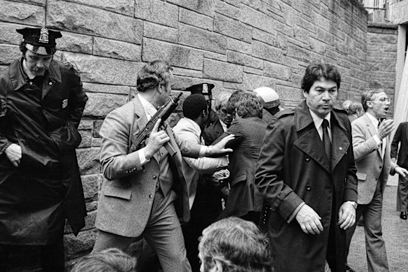 Secret Service agents and police officers swarm John Hinckley Jr (obscured from view) after he opened fire on president Ronald Reagan outside the Washington Hilton.