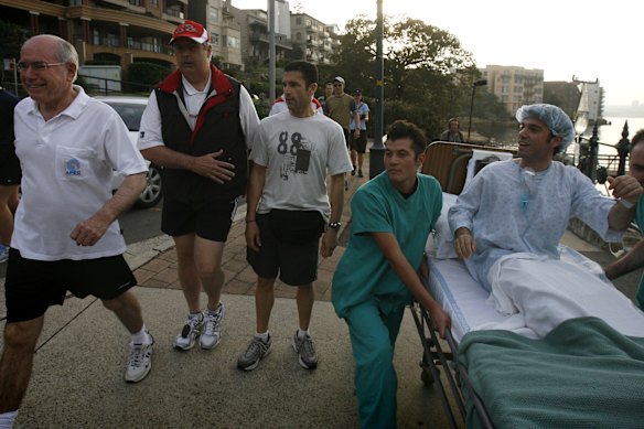 Chas Licciardello, on the hospital bed, chases then prime minister John Howard on his daily walk in Sydney in 2007. 
