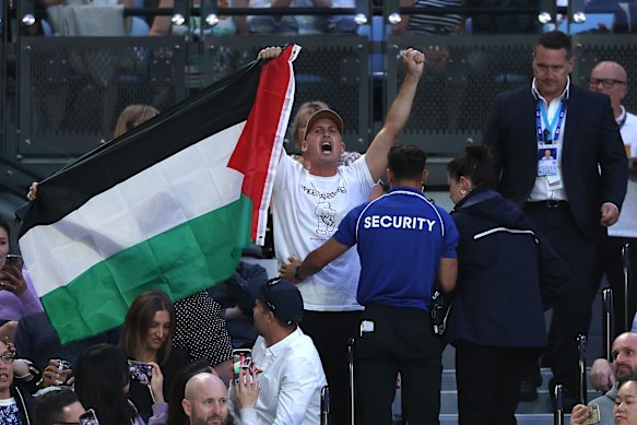 A spectator with a Palestine flag being removed from Rod Laver Arena.