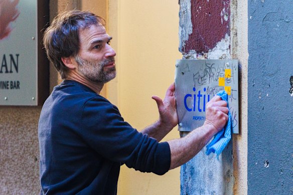 A Miznon staff member cleans graffiti from outside the Melbourne restaurant on Saturday.