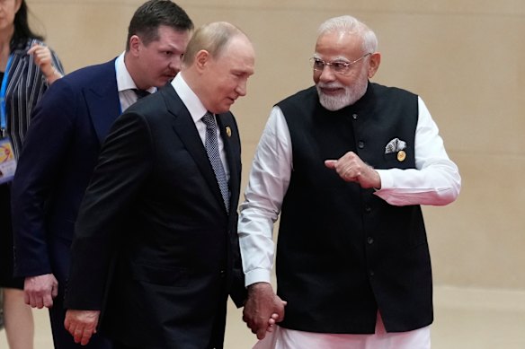 Putin and Modi hold hands.