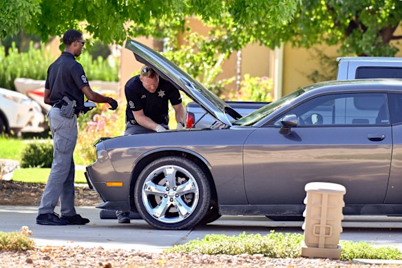 Law enforcement officials examine a silver Dodge outside the Robinson family home in Washington, Utah on Friday.