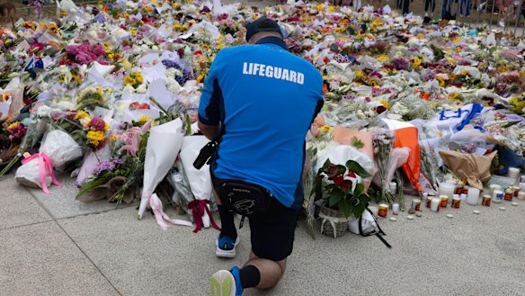 A lifeguard places flowers at the memorial for the mass-shooting victims at the Bondi Pavilion.
