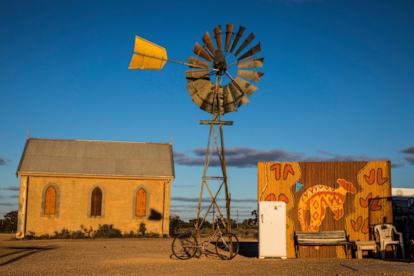 An antique windmill near a historic church creates a classic outback scene in the NSW village of Silverton.