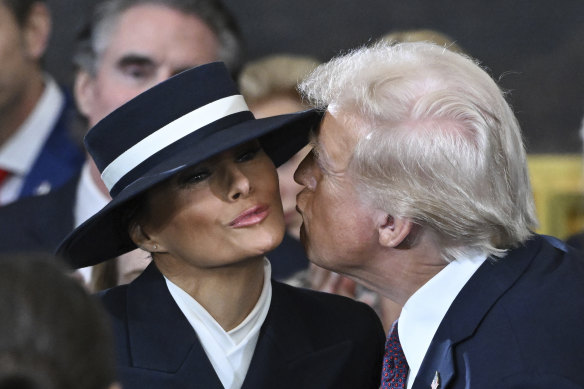 President Donald Trump attempts to kiss First Lady Melania Trump but is blocked by her hat.