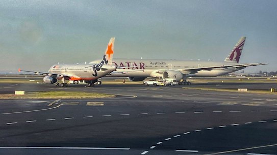 A Jetstar plane and a Qatar Airways plane on the runway at Sydney Airport on Sunday morning.