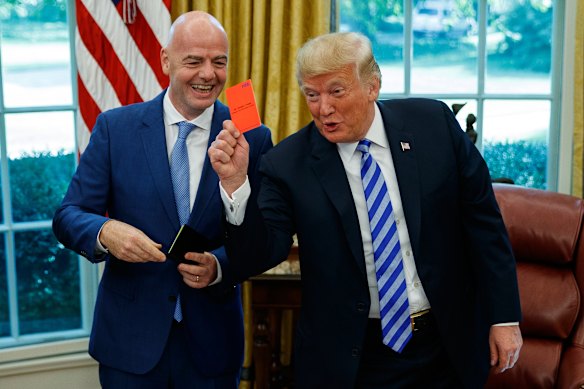 Trump holds up a red card during a meeting with FIFA President Gianni Infantino in the Oval Office in 2018.