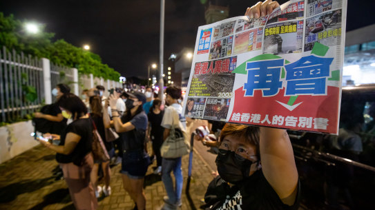 A supporter holds the latest newspaper outside the headquarters of the Apple Daily on Thursday. 