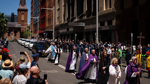 For a brief moment, the city pauses as the procession passes along Phillip Street. 