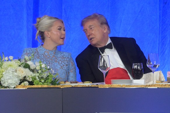 Trump on stage with press secretary Karoline Leavitt.