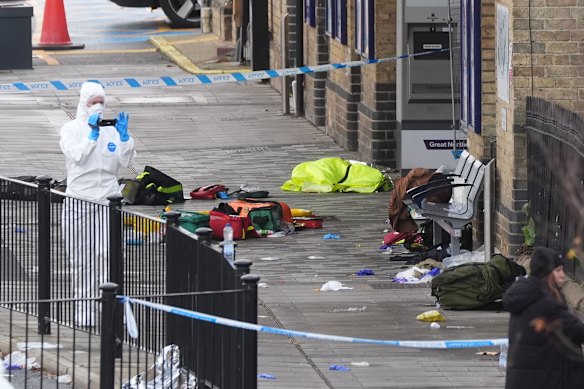 A forensic investigator films the area where passengers abandoned their belongings at Huntingdon station after the mass stabbing on a London-bound train.