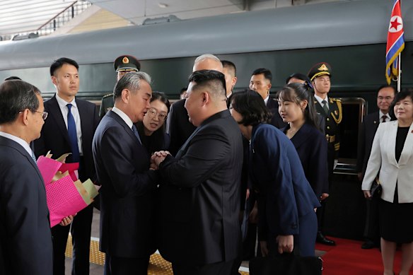 North Korean leader Kim Jong-un, centre, is greeted by Chinese Foreign Minister Wang Yi on his arrival at a train station in Beijing.