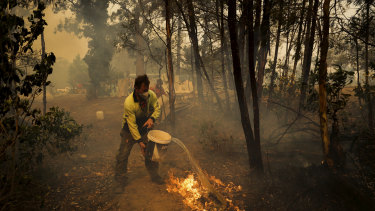 An Oakdale resident defends his home on Friday. Corporate Australia and rich listers have pledged millions of dollars to help firefighters and affected communities.