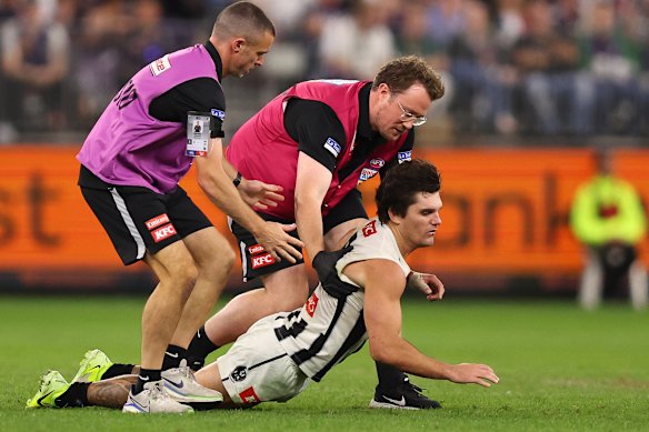 Lachie Schultz of the Magpies collapses in the hands of medical staff.