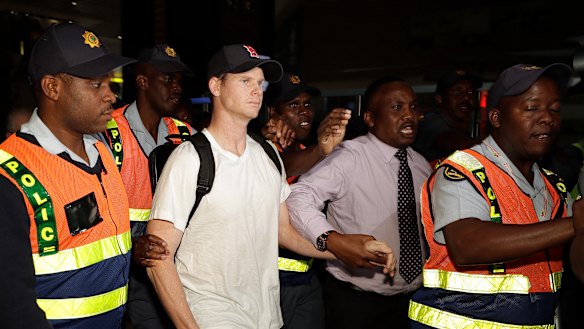Steve Smith escorted by police officers as he leaves Johannesburg after being sent home.