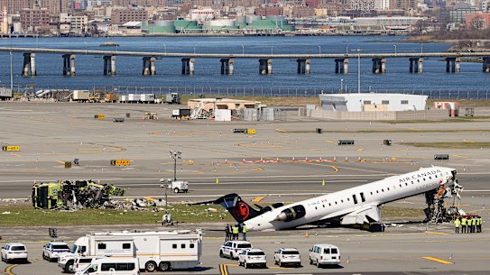 Airport staff inspect the wreckage of the Air Canada aircraft, with the remains of the fire truck shown to the left.