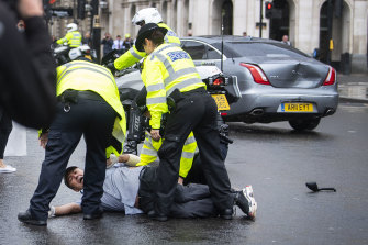 Police detain a man after running in front of Britain's Prime Minister Boris Johnson's car, right.