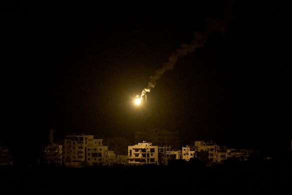 An Israeli army flare drifts over buildings destroyed during the Israeli ground and air operations in the northern Gaza Strip.