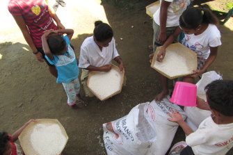 Children sifting rice at the shelter.