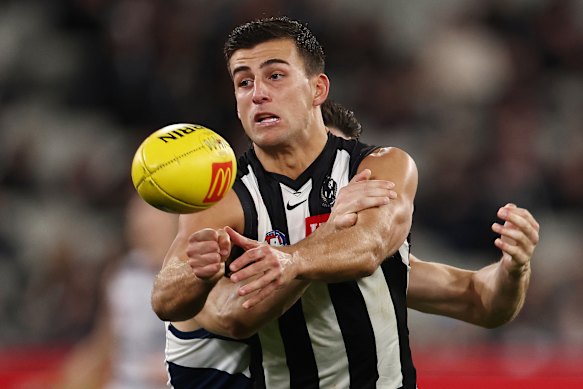 Nick Daicos battles to get a handball away against the Cats.