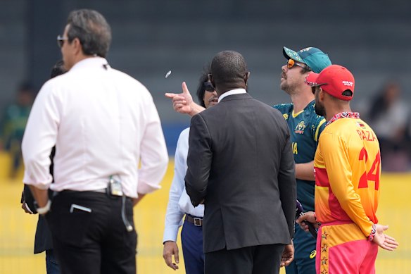 Australia’s captain Travis Head, second right, toss the coin as Zimbabwe’s captain Sikandar Raza, right, makes his call.