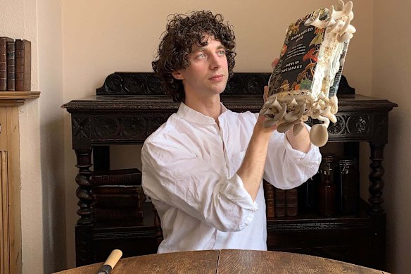 Sheldrake with oyster mushrooms growing from a copy of his book <i>Entangled Life</i>.