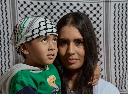 Tanjina Ahmed her four-year-old son Hamza, who is wearing a Palestinian keffiyeh, in front of a keffiyeh-printed wall.