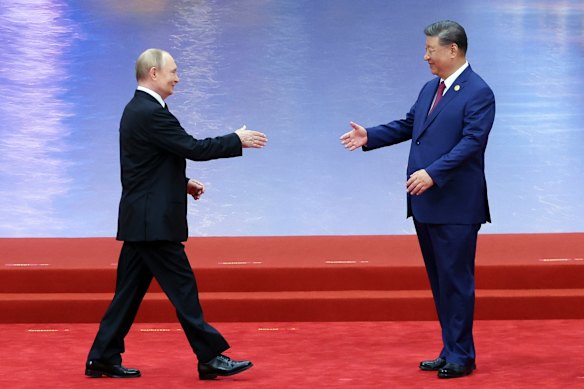 Vladimir Putin, left, and Xi Jinping shake hands during a ceremony to welcome heads of state.