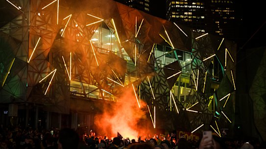 Soccer fans celebrate with a flare at Federation Square during the Matildas vs Denmark World Cup match.