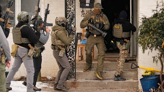 Federal immigration officers ram the door of a Minneapolis home to make an arrest.